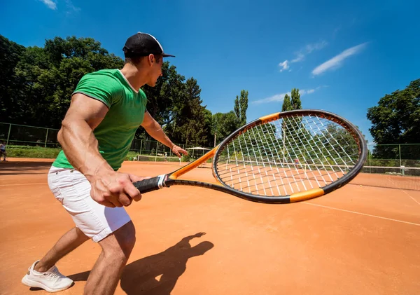 Joven atlético jugando al tenis en la cancha. — Foto de Stock