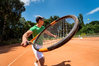 Sahada tenis oynayan genç bir atletik..
