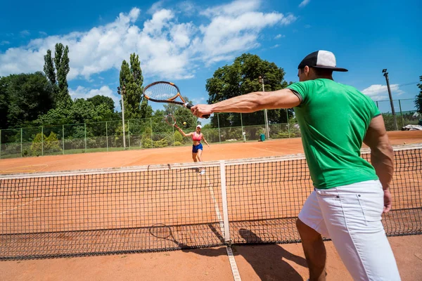 Joven pareja atlética jugando al tenis en la cancha. — Foto de Stock