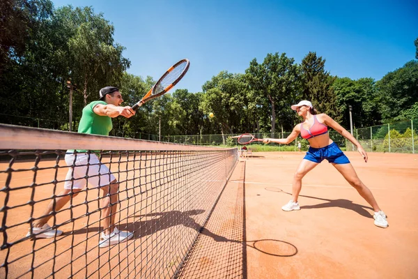 Sahada tenis oynayan genç atletik çift.