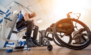 Tekerlekli sandalyeden ayrı olarak egzersiz yapan engelli bir adam..