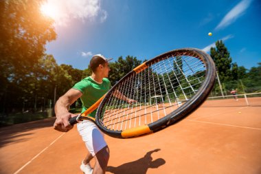 Sahada tenis oynayan genç bir atletik..