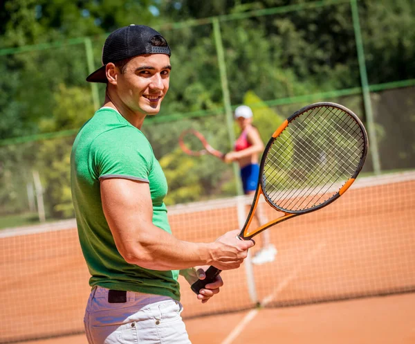 Unga atletiska par spelar tennis på planen. — Stockfoto