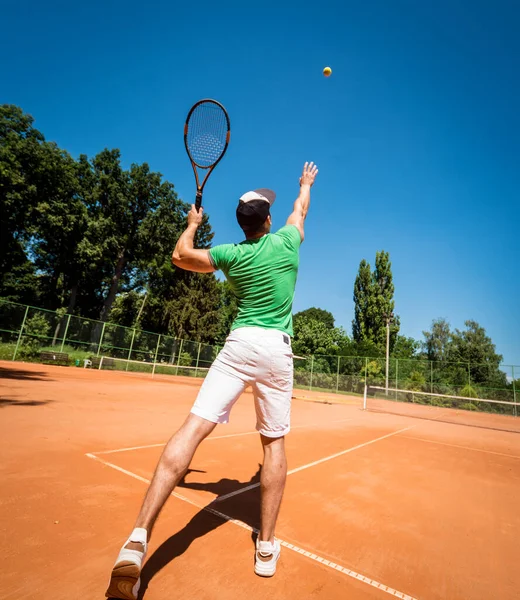 Ung atletisk man spelar tennis på planen. — Stockfoto