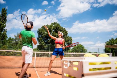 Genç atletik kadın antrenörüyle tenis oynuyor..