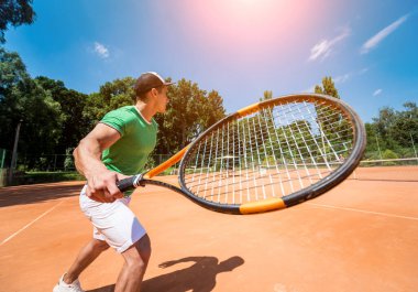 Sahada tenis oynayan genç bir atletik..