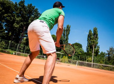 Sahada tenis oynayan genç bir atletik..