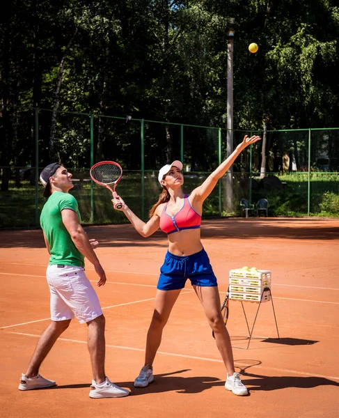 Genç atletik kadın antrenörüyle tenis oynuyor..