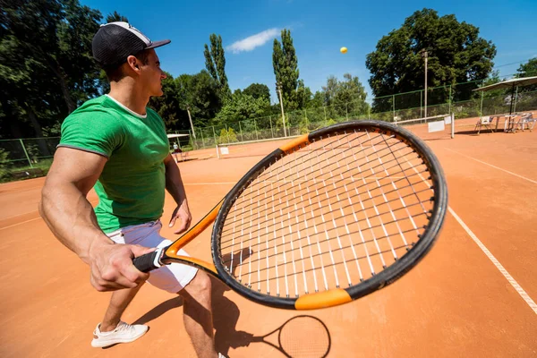 Joven atlético jugando al tenis en la cancha. — Foto de Stock