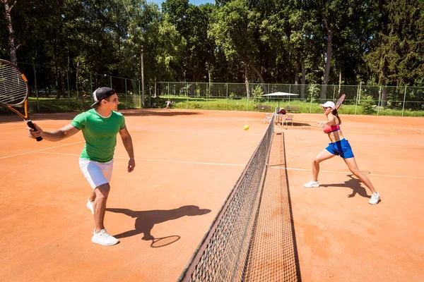 Sahada tenis oynayan genç atletik çift.