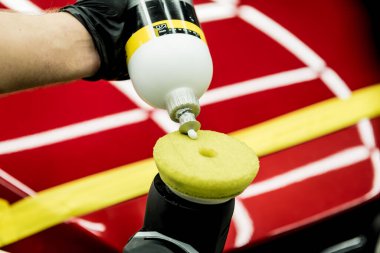 Araba servisi çalışanı, araba detaylarını yörünge cilasıyla parlatıyor..