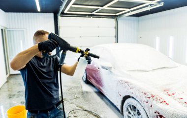 Araba yıkamada köpüklü araba yıkayan bir işçi..