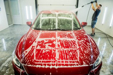 İşçi oto yıkamada yüksek basınçlı suyla araba yıkıyor..