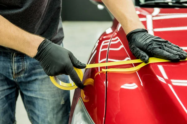 Bil servicearbetare tillämpa skyddstejp på bilen detaljer innan polering. — Stockfoto