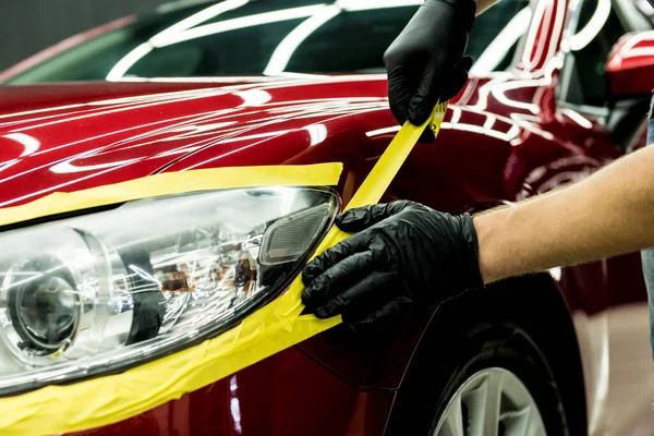 Bil servicearbetare tillämpa skyddstejp på bilen detaljer innan polering. — Stockfoto