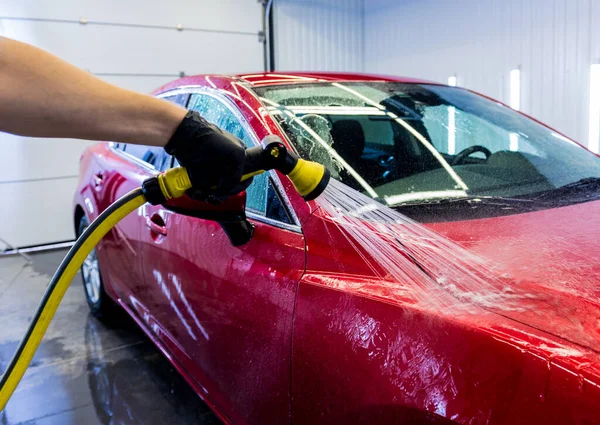 Pracownik serwisu myje samochód w myjni samochodowej. — Zdjęcie stockowe