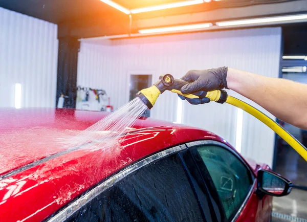 Servisní pracovník mytí aut na myčce aut. — Stock fotografie
