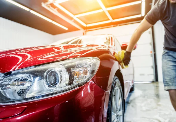 Arbeiter wäscht rotes Auto mit Schwamm in Waschanlage — Stockfoto