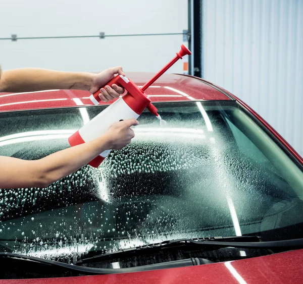 자동차 세차장에서 거품이 활발하게 뿜어 져 나오는 자동차를 청소하는 일꾼. — 스톡 사진