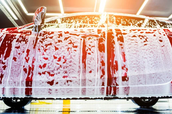 Mytí červeného auta s aktivní pěnou na mytí aut. — Stock fotografie