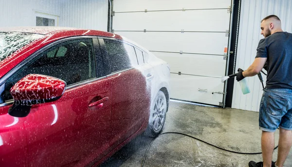 Trabajador de lavado de coches con espuma activa en un lavado de coches. — Foto de Stock