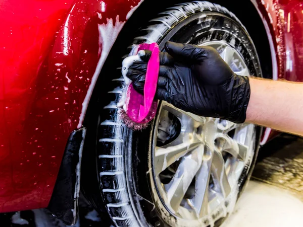 Limpieza de la rueda del coche con un cepillo y agua — Foto de Stock