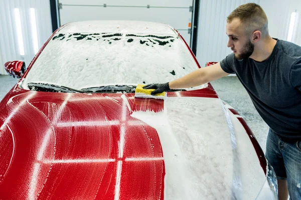 자동차 세차장에서 스펀지를 사용하여 붉은 차를 씻는 작업자 — 스톡 사진