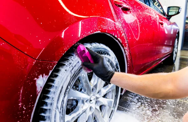 Limpieza de la rueda del coche con un cepillo y agua — Foto de Stock