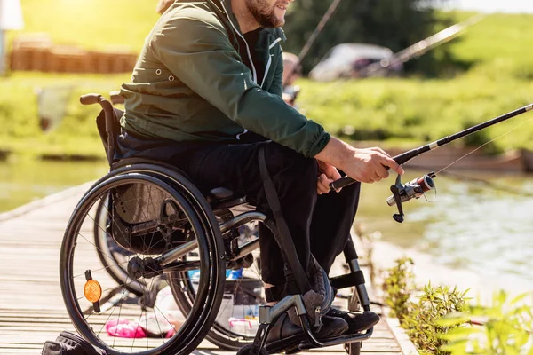 Joven hombre discapacitado en una silla de ruedas pesca. — Foto de Stock