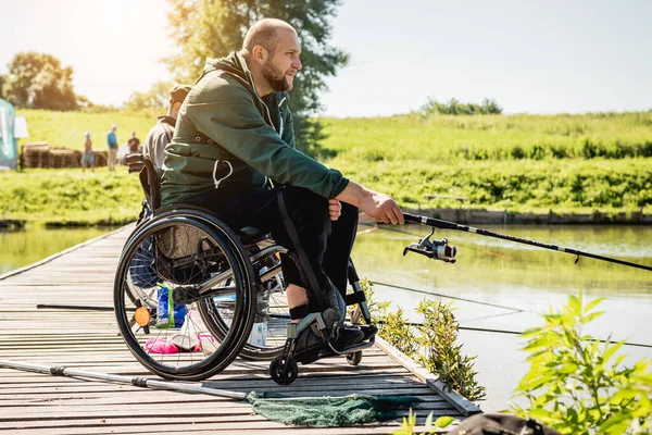 Joven hombre discapacitado en una silla de ruedas pesca. — Foto de Stock