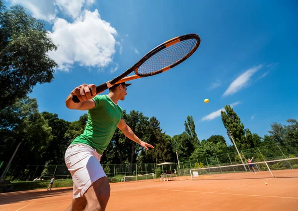 Ung atletisk man spelar tennis på planen. — Stockfoto