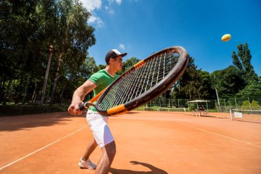 Sahada tenis oynayan genç bir atletik..