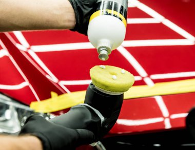 Araba servisi çalışanı, araba detaylarını yörünge cilasıyla parlatıyor..