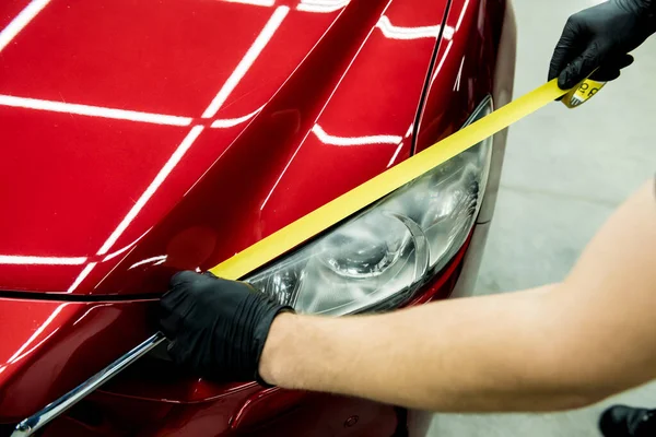 Trabalhador de serviço de carro aplicando fita protetora nos detalhes do carro antes de polir. — Fotografia de Stock