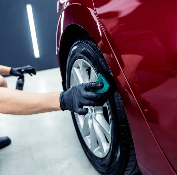 Araba servisi çalışanı mikro fiber bezle araba tekerleklerini parlatıyor..