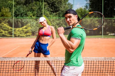 Sahada tenis oynayan genç atletik çift.