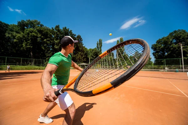 Joven atlético jugando al tenis en la cancha. — Foto de Stock