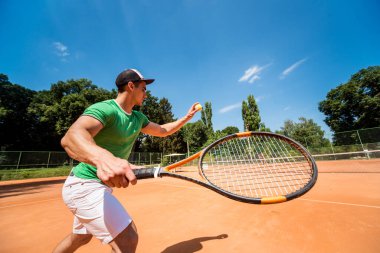 Sahada tenis oynayan genç bir atletik..