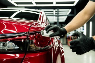 Araba servisi çalışanı bir araba detayına nano kaplama uyguluyor..