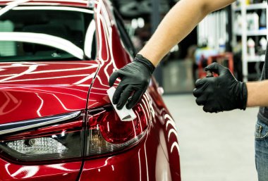 Araba servisi çalışanı bir araba detayına nano kaplama uyguluyor..