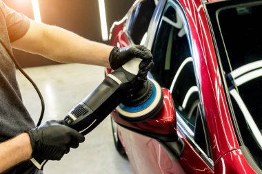 Araba servisi çalışanı, araba detaylarını yörünge cilasıyla parlatıyor..