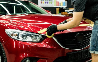 Araba servisi çalışanı, araba detaylarını yörünge cilasıyla parlatıyor..