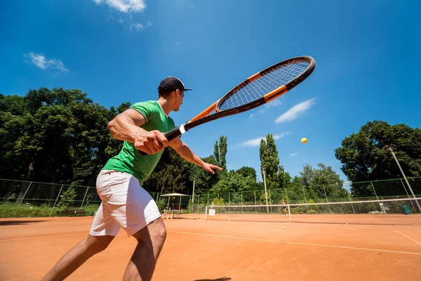Junger athletischer Mann spielt Tennis auf dem Platz. — Stockfoto