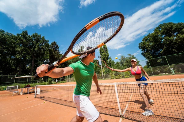 Joven pareja atlética jugando al tenis en la cancha. — Foto de Stock