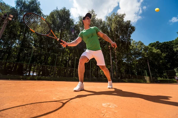 Joven atlético jugando al tenis en la cancha. — Foto de Stock