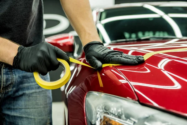 Bil servicearbetare tillämpa skyddstejp på bilen detaljer innan polering. — Stockfoto