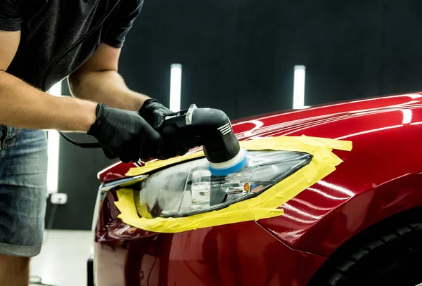 Pracovník autoservisu leští detaily auta s orbitálním leštičem. — Stock fotografie