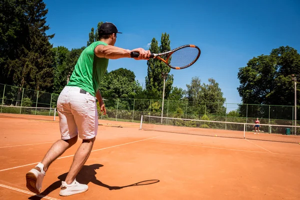 Młody sportowiec gra w tenisa na korcie. — Zdjęcie stockowe