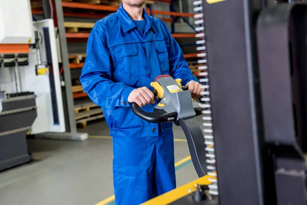 Un trabajador en un almacén utiliza un apilador manual para transportar paletas. — Foto de Stock