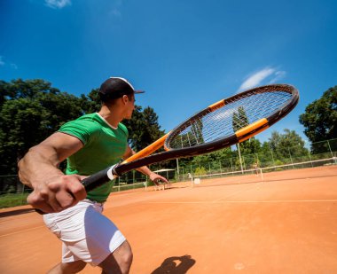 Sahada tenis oynayan genç bir atletik..